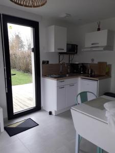 een keuken met witte kasten en een deur naar een tuin bij Le Grand Chêne in Condette