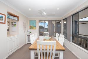 uma sala de jantar com uma mesa e cadeiras brancas em Hibbard 24 em Port Macquarie