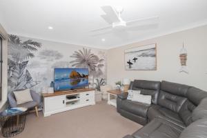 uma sala de estar com um sofá e uma televisão de ecrã plano em Hibbard 24 em Port Macquarie