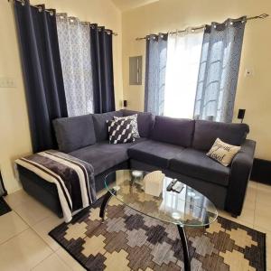 a living room with a couch and a glass table at Gated Cozy Urban Luxe Retreat in Portmore