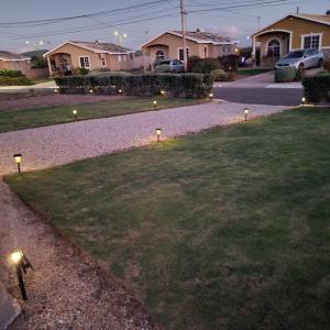 a row of lights in the grass in a yard at Gated Cozy Urban Luxe Retreat in Portmore