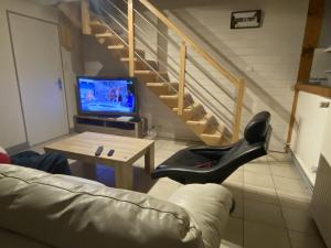 een woonkamer met een bank, een tv en een trap bij Clos Saint Hilaire in Longeville-sur-Mer