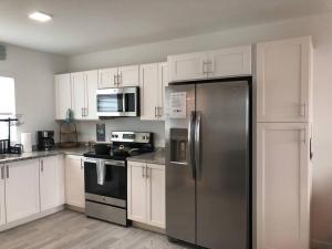 a kitchen with white cabinets and a stainless steel refrigerator at THE SANDCASTLE SUITE! Brand New 2Bedroom in Oceanfront Complex! BE THE FIRST to Visit our Condo Townhome with FREE Parking & Private Garage at Ocean Isles 38 Marathon FL KEYS! SPECIAL PRICING!!! in Marathon