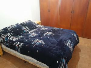 a bed with a blue comforter on top of it at Arai casa alquiler turistico in Oberá