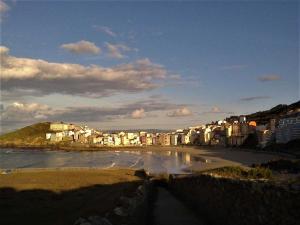 Blick auf einen Strand mit Gebäuden und das Meer in der Unterkunft Dachwohnung mit Terasse und Meerblick unweit des Strandes in Malpica