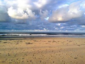 ein Strand mit bewölktem Himmel und dem Meer in der Unterkunft Dachwohnung mit Terasse und Meerblick unweit des Strandes in Malpica