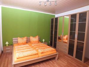 um quarto verde com uma cama grande com almofadas laranja em Ferienwohnung Klaus em Steinach