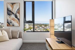uma sala de estar com um sofá e uma televisão de ecrã plano em Modern Urban Oasis 2 bed Apartment em Melbourne
