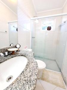 een badkamer met een douche, een wastafel en een toilet bij Apto Varanda Verde com Lareira in Campos do Jordão