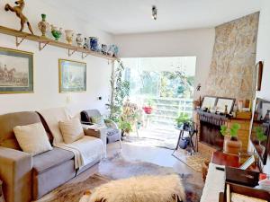 a living room with a couch and a large window at Apto Varanda Verde com Lareira in Campos do Jordão