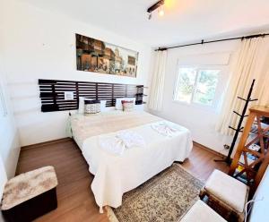 een slaapkamer met een groot wit bed en een raam bij Apto Varanda Verde com Lareira in Campos do Jordão