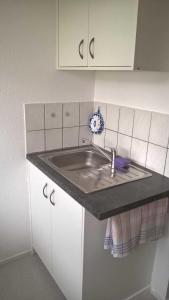 um balcão de cozinha com um lavatório e armários brancos em Haus Frey em Badenweiler