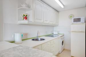 kuchnia z białymi szafkami, zlewem i lodówką w obiekcie Duquesa 506 by IVI Real Estate w mieście Torremolinos