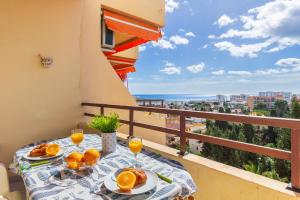 balkon ze stołem z jedzeniem i kieliszkami soku pomarańczowego w obiekcie Duquesa 506 by IVI Real Estate w mieście Torremolinos