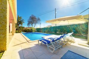 uma piscina com duas cadeiras e um guarda-sol e uma mesa e uma piscina em Villa Paraiso em São Bartolomeu de Messines