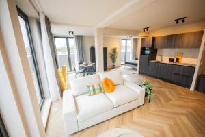 a living room with a white couch and a kitchen at Alphabet Studio Apartments Penthouse KS71 in Hilversum
