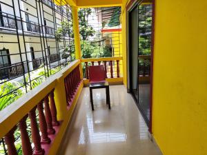 uma cadeira sentada na varanda de um edifício amarelo em Maria Comfort Stay em Calangute