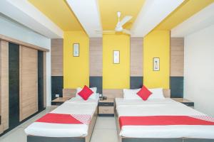 - 2 lits dans une chambre avec des oreillers jaunes et rouges dans l'établissement OYO 8501 ABHIMAANI COMFORTS, à Bangalore