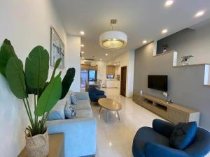 sala de estar con sofás azules y TV en Royal Lotus Hạ Long Resort - kiko resort en Ha Long