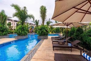 下龍灣的住宿－Royal Lotus Hạ Long Resort - kiko resort，一个带椅子和遮阳伞的游泳池