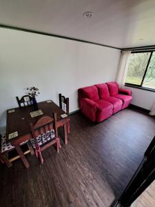 uma sala de estar com um sofá vermelho e uma mesa em La Cabaña del Bosque em Delicias