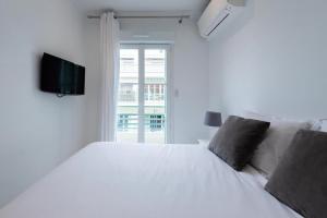 um quarto com uma cama branca e uma televisão na parede em CENTER JUAN LES PINS 50 M DES PLAGES em Antibes