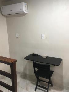 mesa negra con silla y aire acondicionado en la pared en Residencial Estrela Guia 2, en Cabo Frío