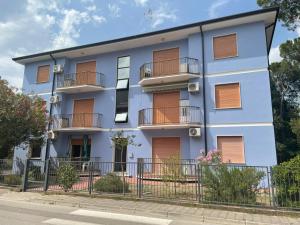 um edifício azul com varandas numa rua em Giovanna em Rosolina Mare