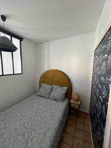 een slaapkamer met een bed met een houten hoofdeinde bij La Tranche Cozy Stay! in La Tranche-sur-Mer