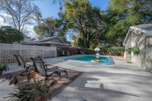 a backyard with a pool and chairs and a fence at Pool house w/lg yard in the heart of Tampa in Tampa