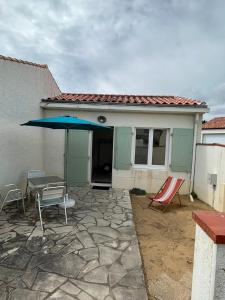 een patio met een tafel en een blauwe parasol bij La Tranche Cozy Stay! in La Tranche-sur-Mer