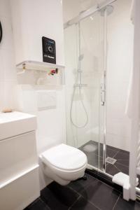y baño blanco con aseo y ducha. en Villa Escudier Appart-hôtel, en Boulogne-Billancourt