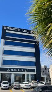 a hotel with cars parked in front of a building at NIYAMA LAND HOTEL in Umm Lujj