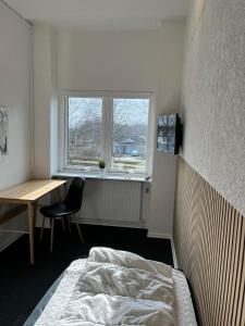 um quarto com uma cama, uma secretária e uma janela em rooms for rent Andersen Invest em Skjern