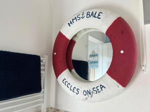 a red and white first rate mirror on a wall at Fun family beach house! in Lessingham