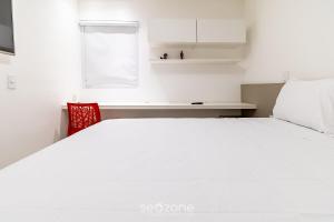 a bedroom with a white bed and a red chair at Excelente apt em Maceio/AL 850m da praia ADV306 in Maceió