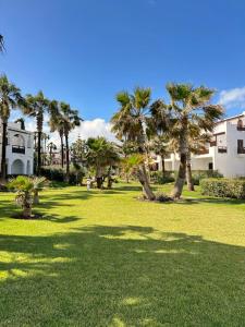 un parc avec des palmiers et un bâtiment dans l'établissement Ksar Rimal par IMMO MARINA Vacances de Rêve G, à Marina Smir