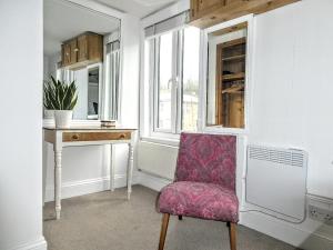 a room with a chair and a desk and a window at Victoria Cottage in St. Agnes