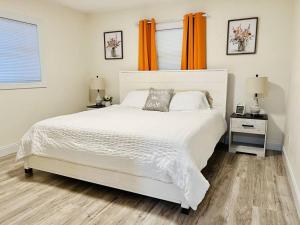 a bedroom with a large white bed with orange curtains at Country Welcome in Micanopy