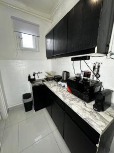 - une cuisine avec des placards noirs et un comptoir en marbre dans l'établissement Airport17 B&B, à Vecsés