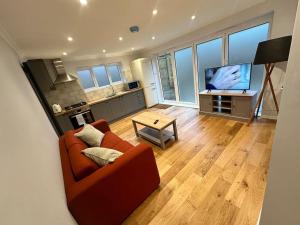un salon avec un canapé orange et une télévision dans l'établissement Lovely Relaxing One Bedroom Flat, à Royal Tunbridge Wells