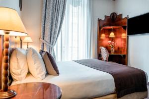 a hotel room with a bed with a table and a window at Villa Montparnasse in Paris