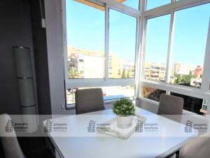 einen Tisch mit einer Topfpflanze darauf in einem Zimmer mit Fenstern in der Unterkunft 645 Águila Apartamentos - Vista al mar - Cerca de tren, restaurantes, tiendas - PLAYA A 10 MIN CAMINANDO in Benalmádena