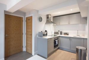 a kitchen with white cabinets and a wooden door at Modern,central 1 bedroom flat in Brentwood