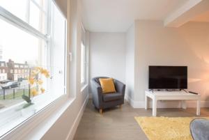 a living room with a tv and a chair and a window at Modern,central 1 bedroom flat in Brentwood