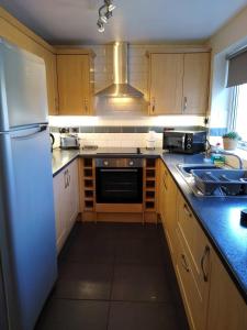 eine Küche mit Holzschränken und einem weißen Kühlschrank in der Unterkunft Escape to Anglesey, Dog Friendly in Llangoed