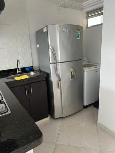 Una cocina con frigorífico de acero inoxidable y fregadero. en Apartamento en San gil, en San Gil
