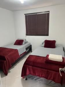 Un dormitorio con dos camas con sábanas rojas y una ventana. en Apartamento en San gil, en San Gil