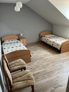 two beds and a chair in a room with wooden floors at Andrzejówka in Cieplice