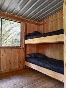 two bunk beds in a wooden cabin with a window at Macheta Climbing House in Machetá